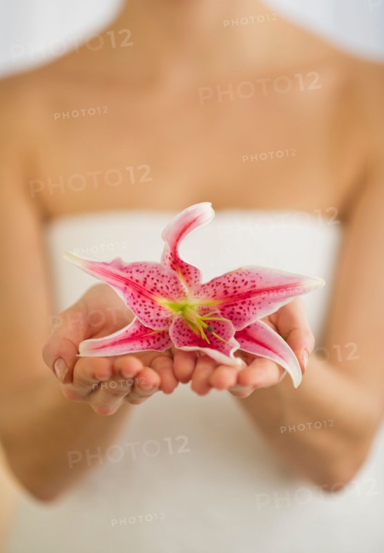 Studio shot of woman holding lily.