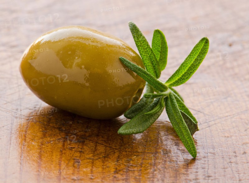 Close-up of green olive with rosemary, studio shot.