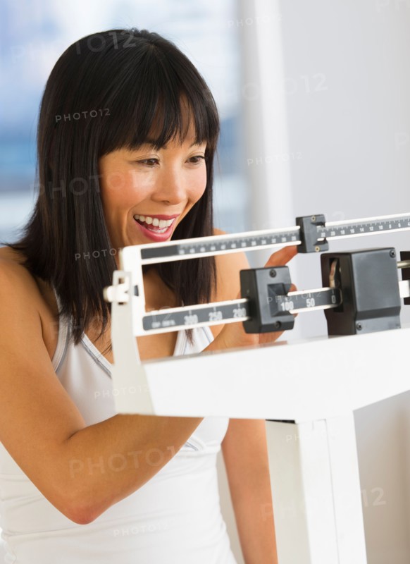 Smiling woman checking her weight.