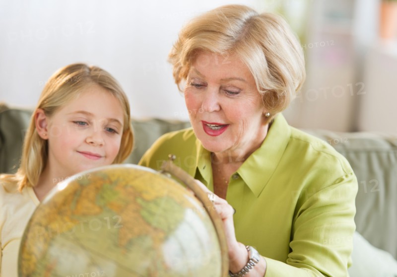 Grandmother with granddaughter (8-9) looking at globe.