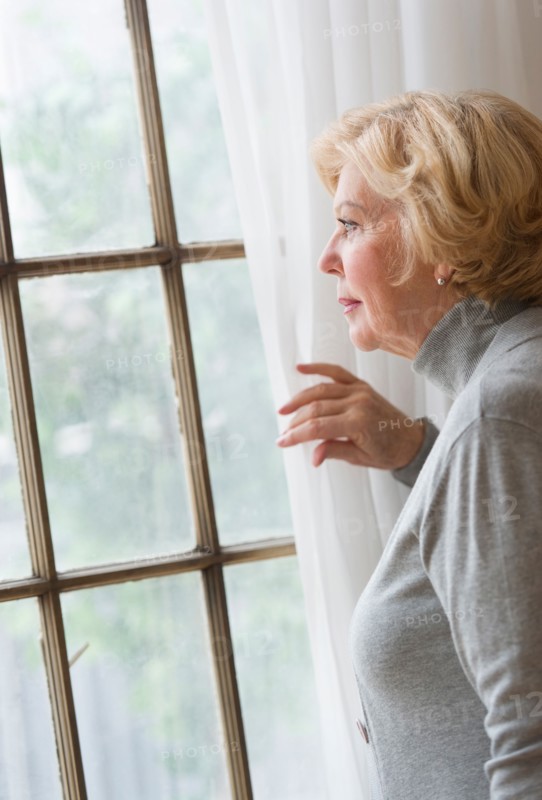 Portrait of senior woman looking through window.