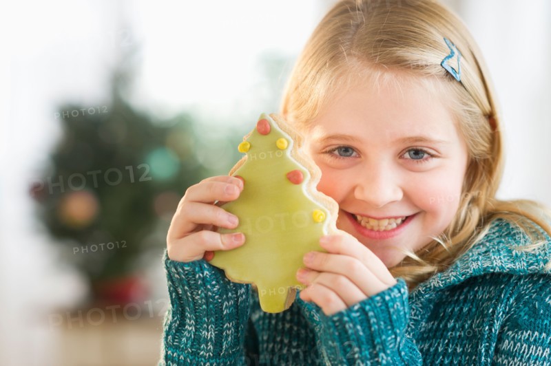 Girl (8--9) holding gingerbread cookie.