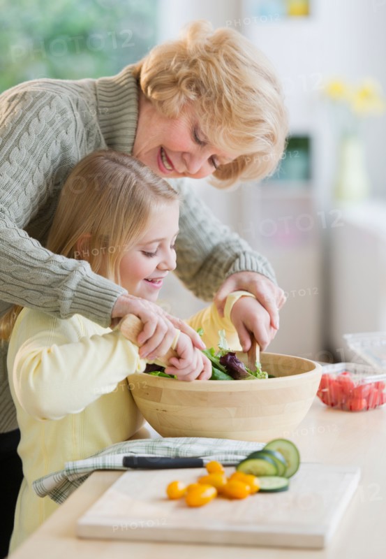 Grandmother and granddaughter (8-9) preparing salad together.