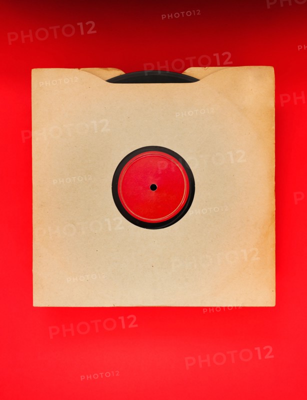 Vinyl record in envelope on red background, studio shot.