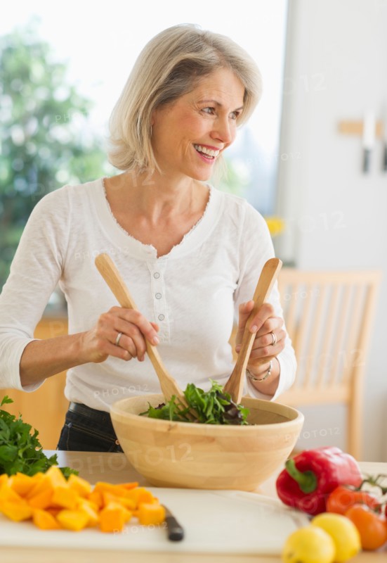 JPortrait of senior woman preparing salad in kitchen.