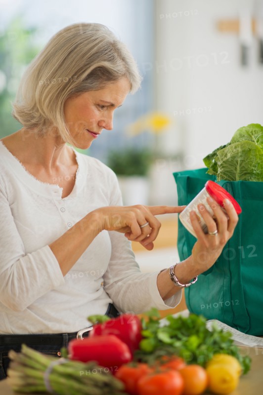Portrait of senior woman checking product in kitchen.