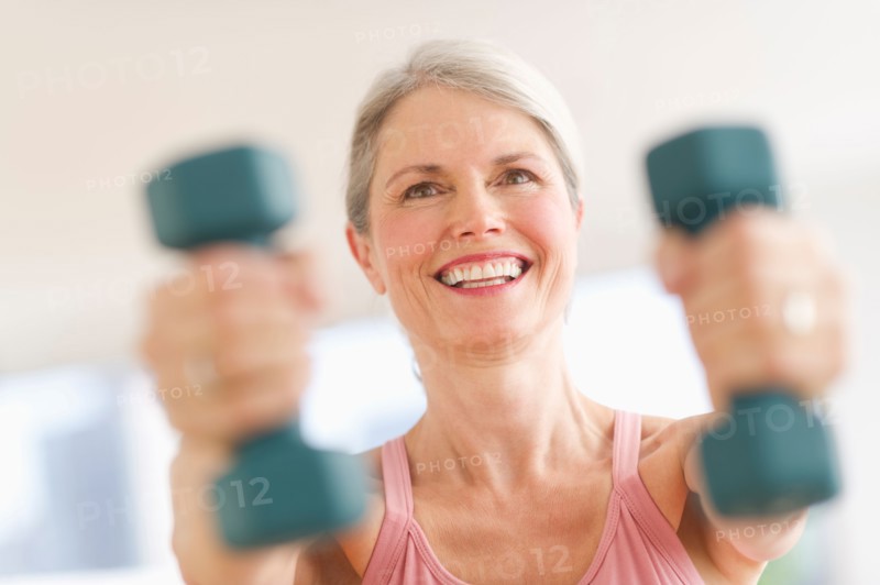 Portrait of senior woman exercising with dumbbells in gym.