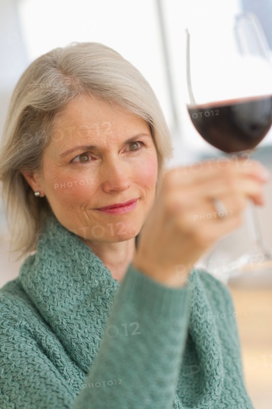 Senior female connoisseur tasting red wine.