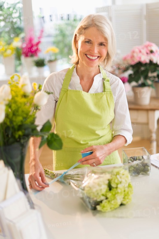 Senior female florist arranging bouquet.