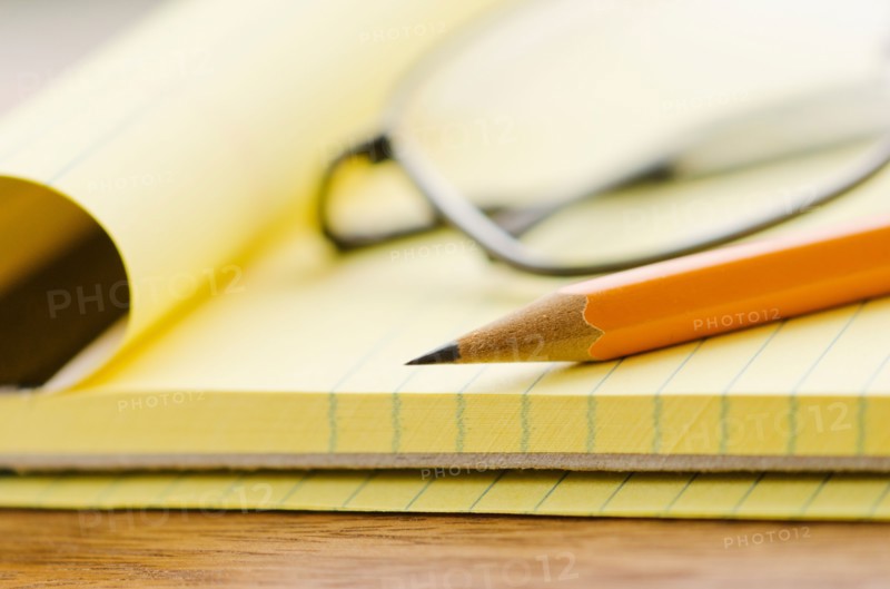 Close up of glasses, notebook and pencil, studio shot.
