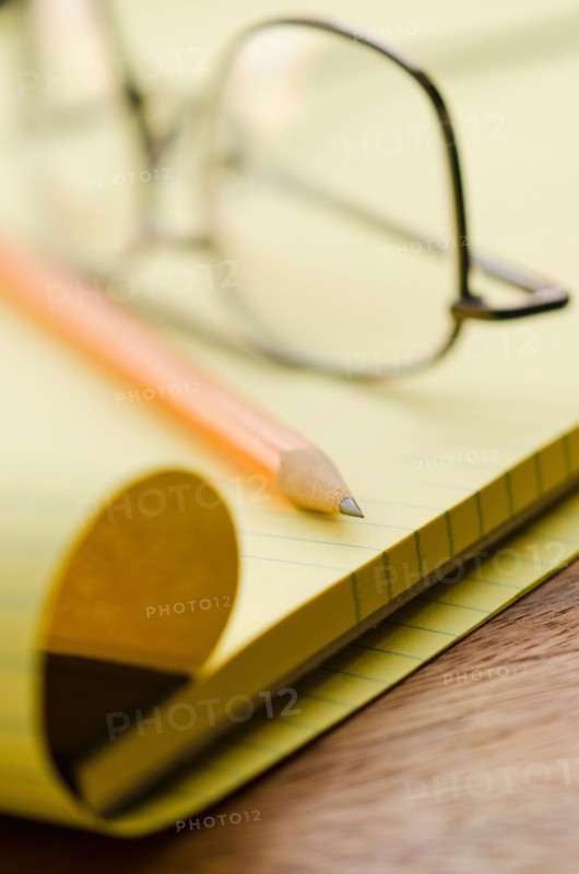 Close up of glasses, notebook and pencil, studio shot.