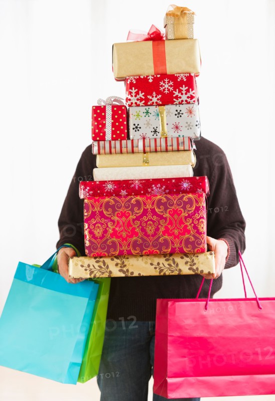 Man carrying stack of Christmas presents, studio shot.
