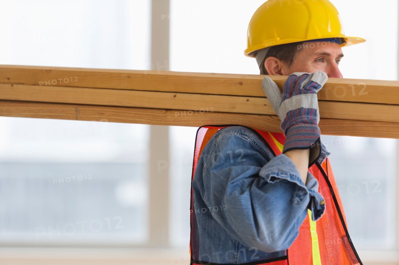 Construction worker carrying planks.