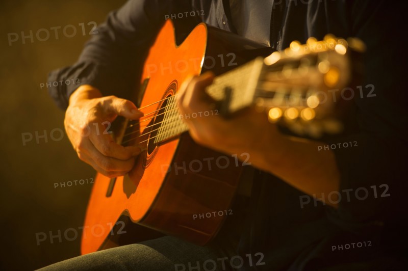 Close up of man playing acoustic guitar, studio shot.