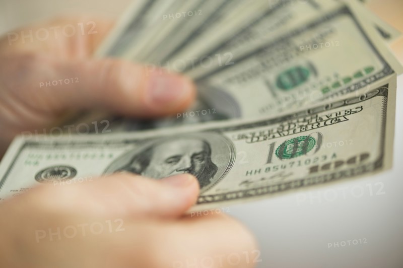 Close up of man's hands counting dollar banknotes.