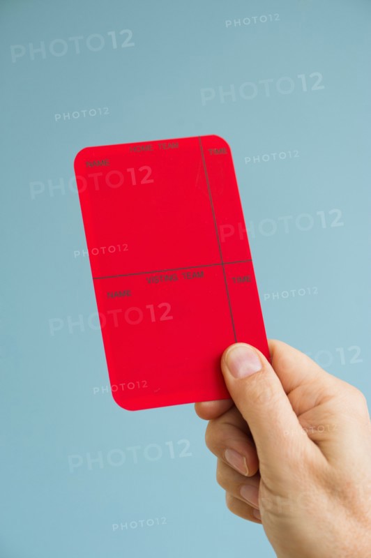 Close up of man's hand showing red card, studio shot.