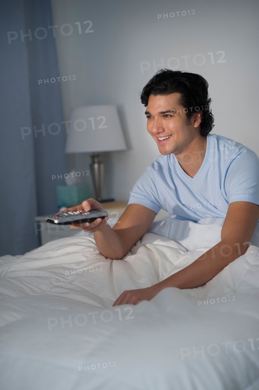 Man watching tv in bed.