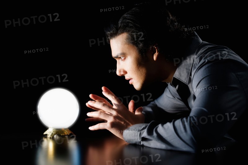 Studio shot of businessman staring at crystal ball.