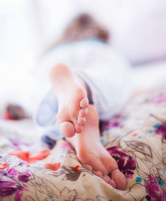 Close-up of woman's feet lying on bed. Photo : Daniel Grill