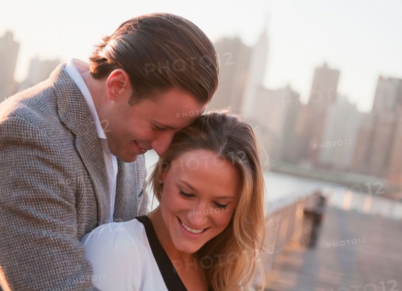 USA, New York, Long Island City, Young couple flirting on bridge, Manhattan skyline in background. Photo : Daniel Grill