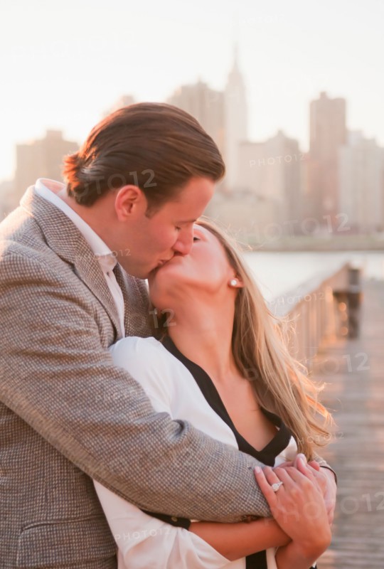 USA, New York, Long Island City, Young couple kissing on boardwalk, Manhattan skyline in background. Photo : Daniel Grill