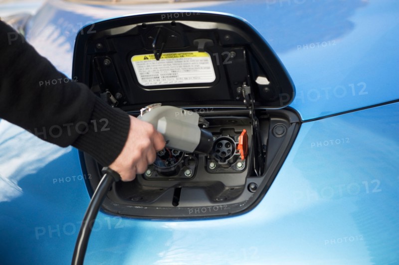 Close-up of man charging electric car. Photo : fotog