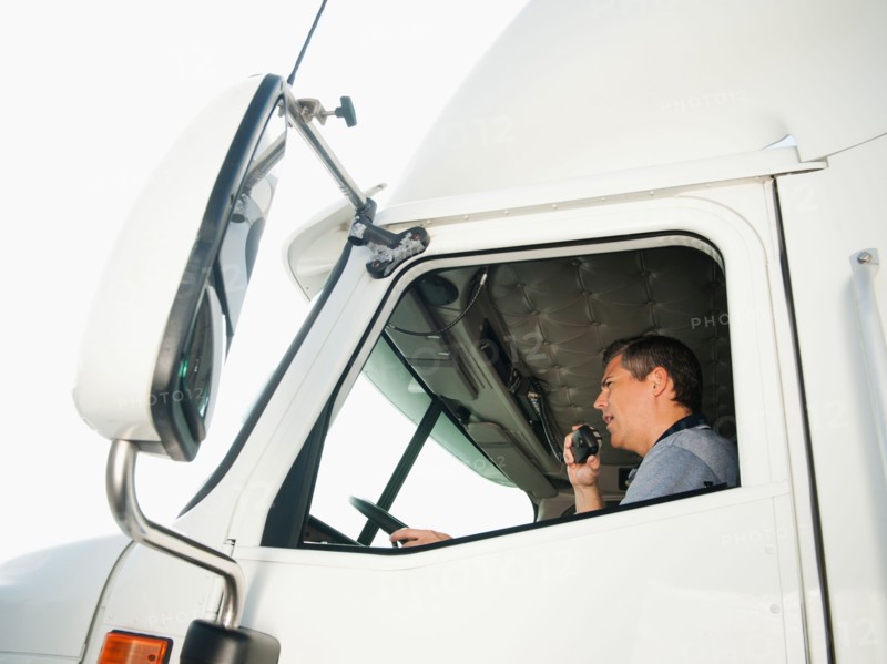 Truck driver sitting in truck and talking on CB radio.