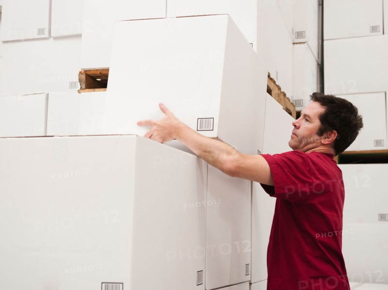 Worker stacking boxes in warehouse.