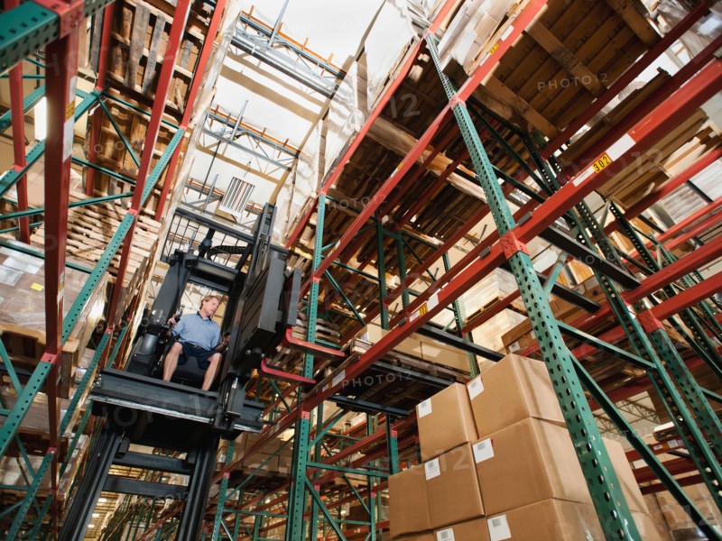 Forklift truck stacking boxes in warehouse.