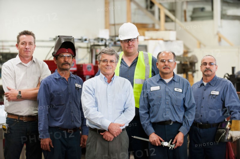 Portrait of businessman and workers in factory.