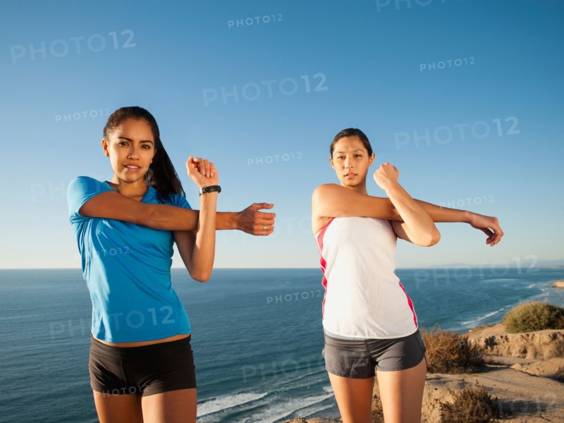 USA, California, San Diego, Two women stretching at sea coast.