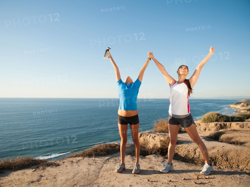 USA, California, San Diego, Two women stretching at sea coast.