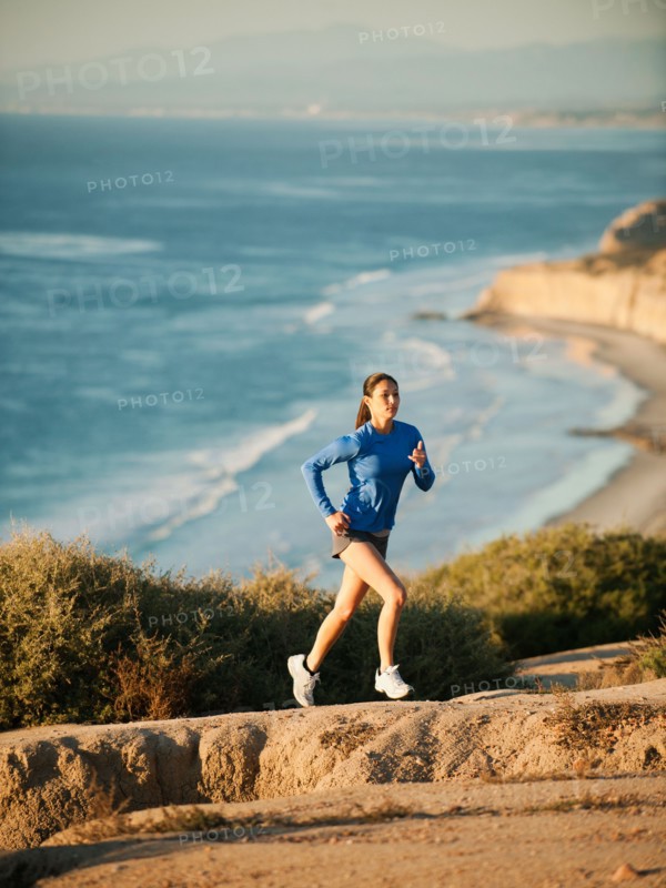 USA, California, San Diego, Woman jogging along sea coast.