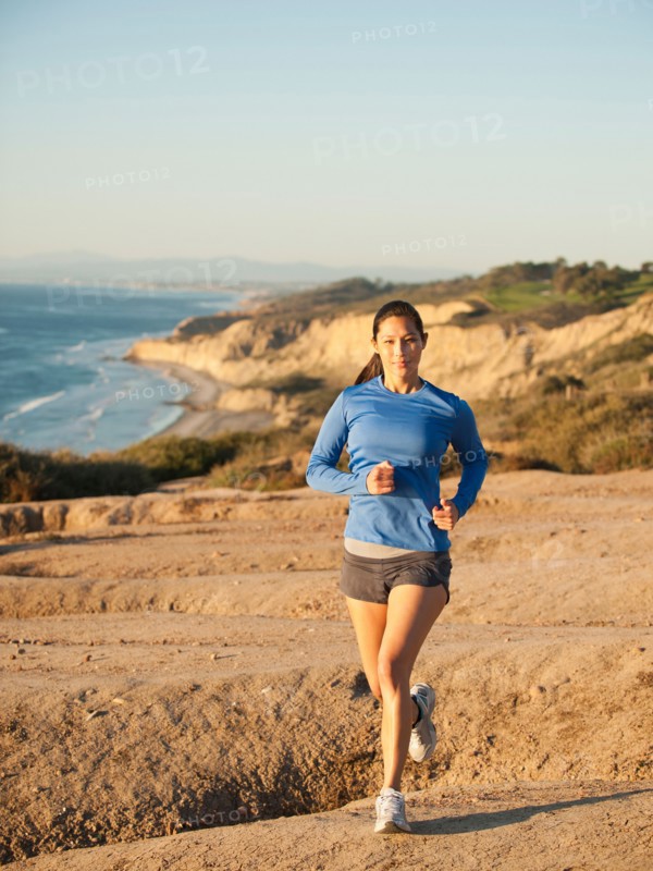 USA, California, San Diego, Woman jogging along sea coast.