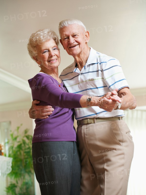 Senior couple dancing at home.
