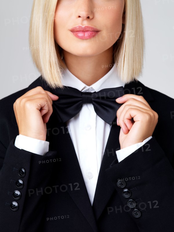 Studio shot of young waitress adjusting bow tie. Photo : Yuri Arcurs