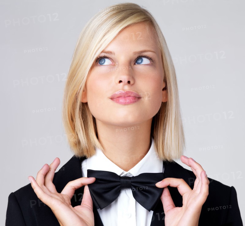 Studio portrait of young waitress adjusting bow tie. Photo : Yuri Arcurs