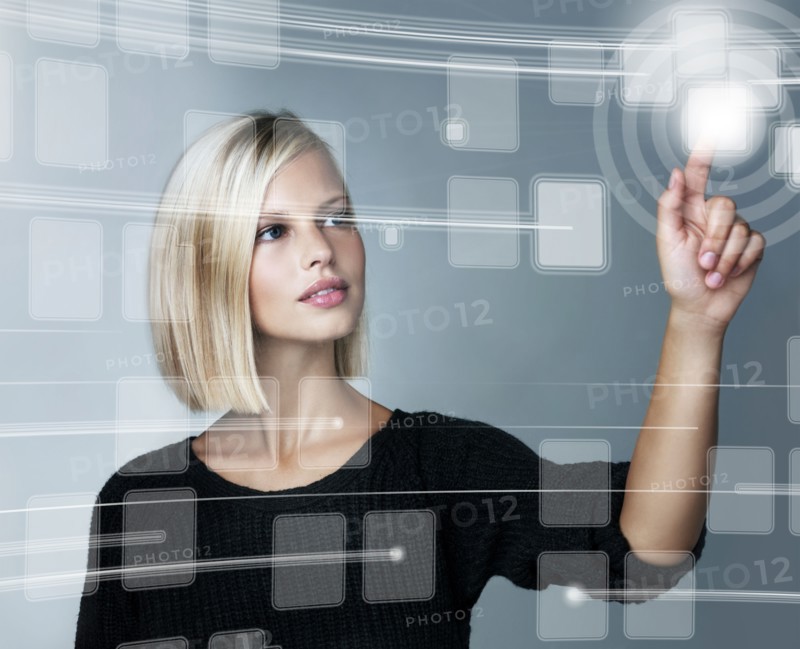 Young woman using futuristic touchscreen, studio shot. Photo : Yuri Arcurs