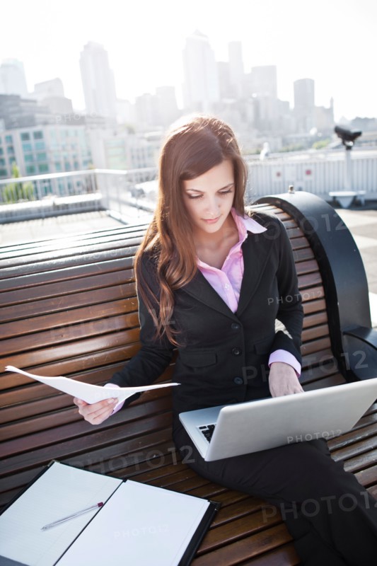 USA, Seattle, Young businesswoman sitting on bench and working. Photo : Take A Pix Media