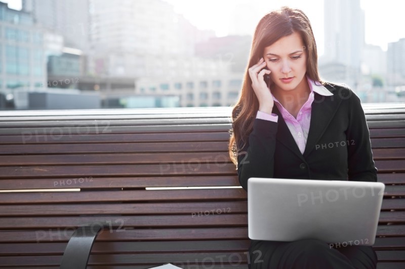 USA, Seattle, Young businesswoman sitting on bench and working. Photo : Take A Pix Media