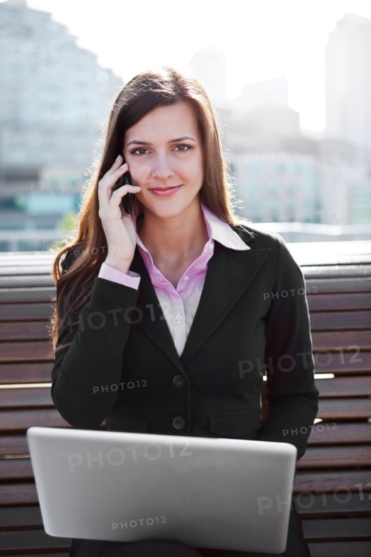 USA, Seattle, Young businesswoman sitting on bench and working. Photo : Take A Pix Media