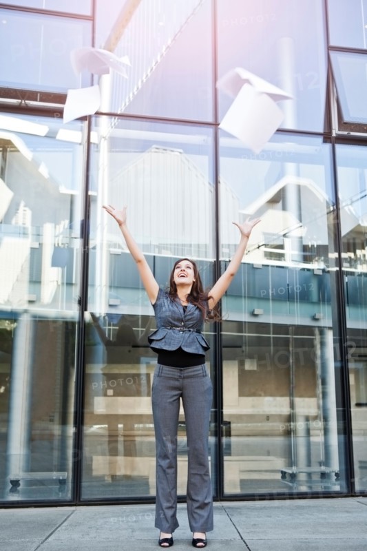 USA, Seattle, Young businesswoman throwing documents in front of office building. Photo : Take A Pix Media