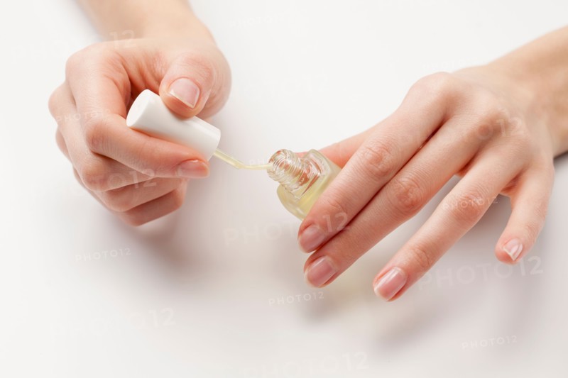 Close up of woman's hands holding nail polish, studio shot. Photo : Jan Scherders