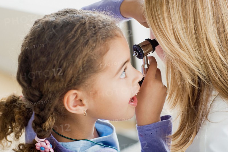 Girl (10-11) examining doctor's ear with otoscope. Photo : Rob Lewine