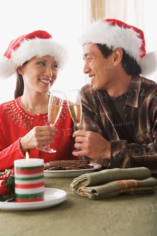 Couple wearing santa hats toasting with champagne. Photo : Rob Lewine