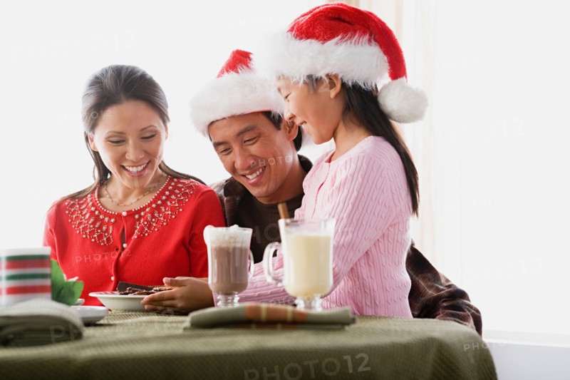 Girl (10-11) wearing Santa hat serving cookies to parents. Photo : Rob Lewine