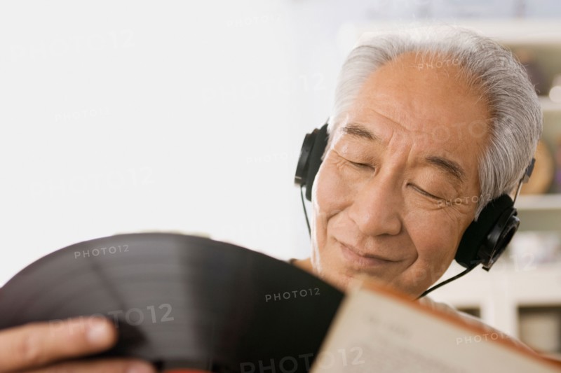 Senior man listening to vinyl record. Photo : Rob Lewine