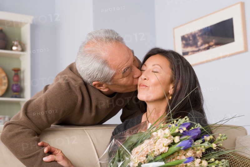 Woman receiving kiss and flowers from husband. Photo : Rob Lewine