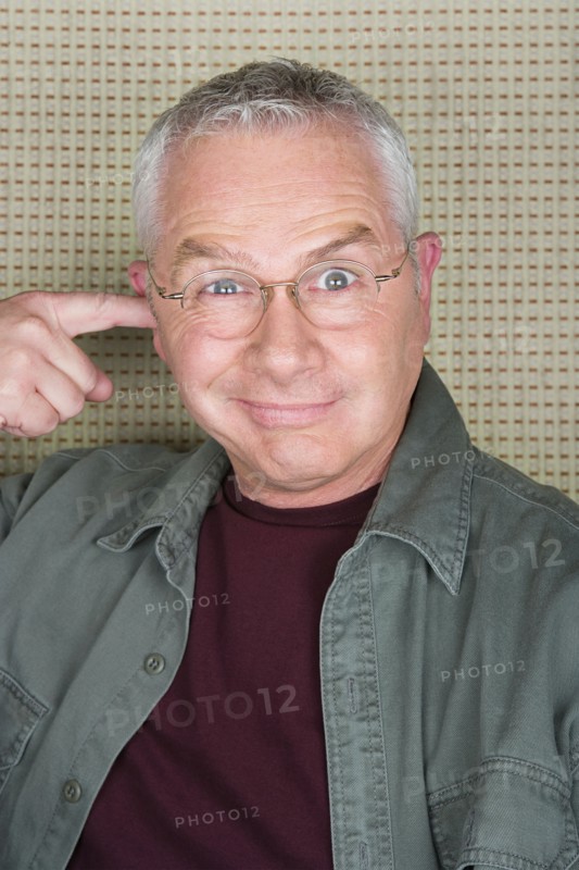Older man putting finger in ear. Photo : Rob Lewine
