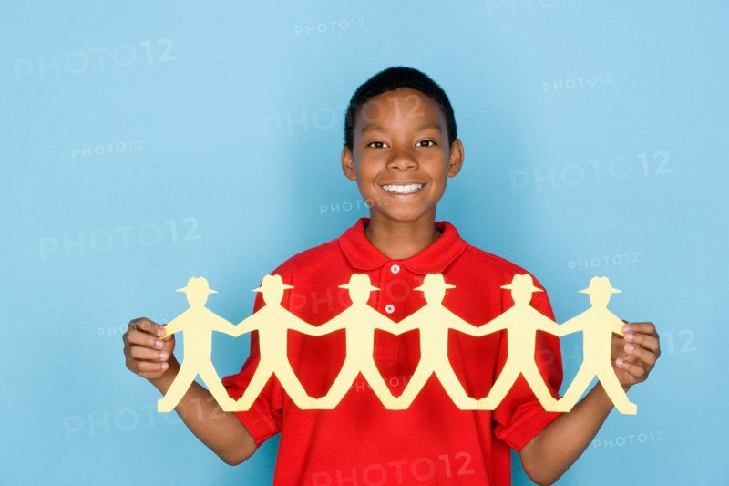 Studio portrait of teenage boy holding paper cutout. Photo : Rob Lewine